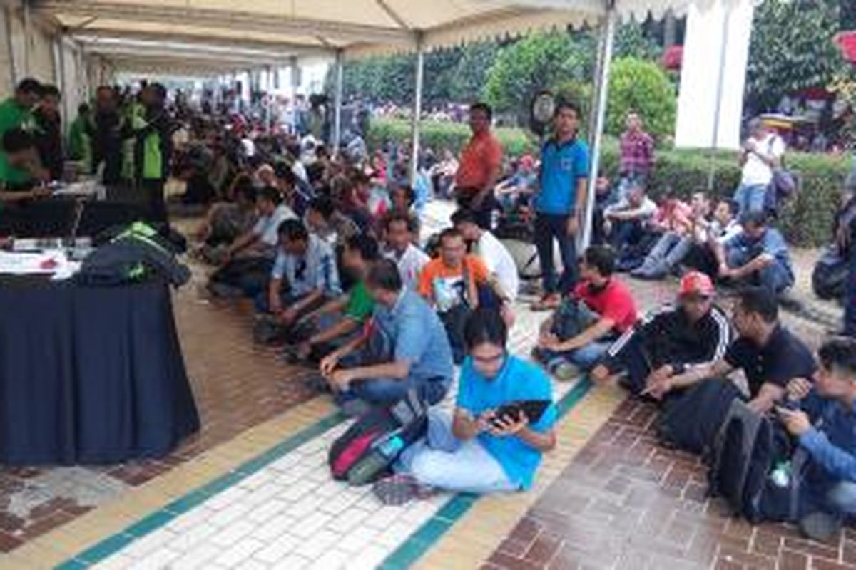 Ribuan pendaftar Grab Bike, duduk lesehan menunggu gilaran registrasi di lapangan parkir barat SUGBK, Senayan, Rabu (13/8/2015).