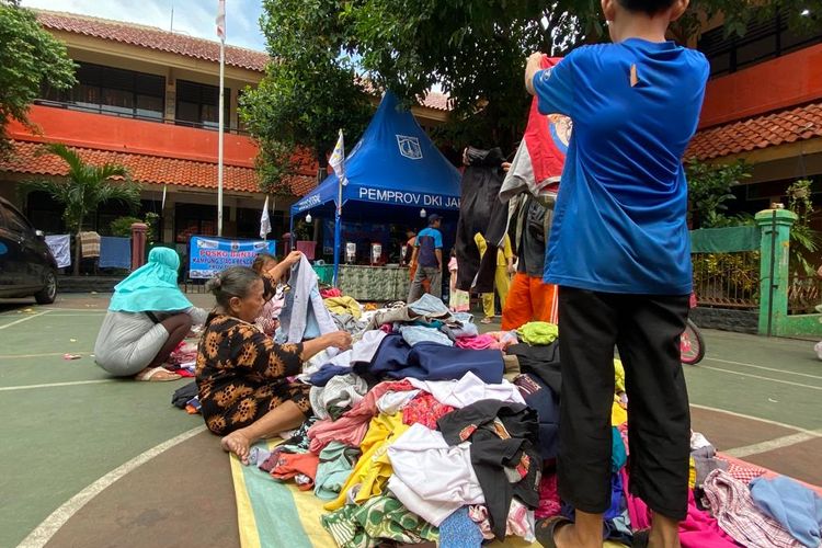 Beberapa warga memilih baju bekas saat mengungsi di posko pengungsian Kompleks SDN Duri Utara, Senin (10/7/2023). Mereka merupakan korban kebakaran yang terjadi di Gang Lontar, Kelurahan Duri Utara, Kecamatan Tambora, Jakarta Barat pada Sabtu (8/7/2023).  