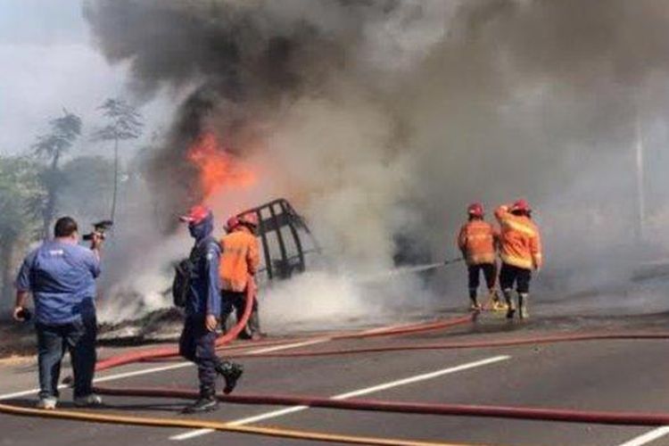 Petugas saat memadamkan api yang membakar truk bermuatan karet di jalan tol Waru - Sidoarjo 
