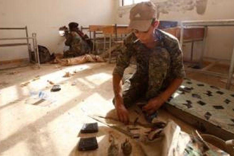 Anggota Unit Perlindungan Rakyat Kurdi mengambil posisi di sebuah ruangan kelas di desa Maarouf di Provinsi Hasakeh, Suriah, dalam pertempuran melawan ISIS, Kamis (16/7/2015).
