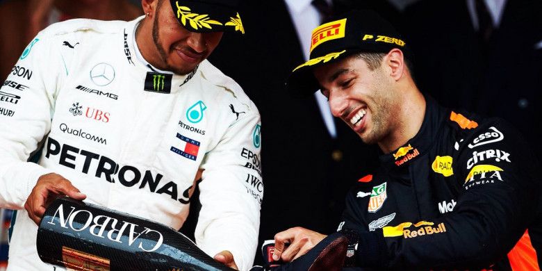 Pebalap Mercedes, Lewis Hamilton (kiri), menuangkan sampanye ke sepatu Daniel Ricciardo selepas balapan F1 GP Monaco di Sirkuit Monaco, Monte Carlo, Monako pada Minggu (27/5/2018).
