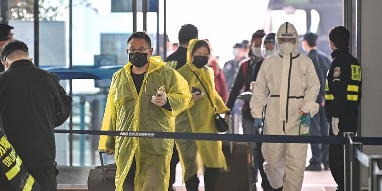 Orang-orang mengenakan pakaian pelindung diri melintas di Bandara Tianhe yang baru dibuka kembali di Wuhan, Hubei, China, Rabu (8/4/2020). Ribuan orang bergegas meninggalkan Wuhan setelah otoritas mencabut kebijakan lockdown selama lebih dari dua bulan di lokasi yang diketahui sebagai episenter awal virus corona tersebut.