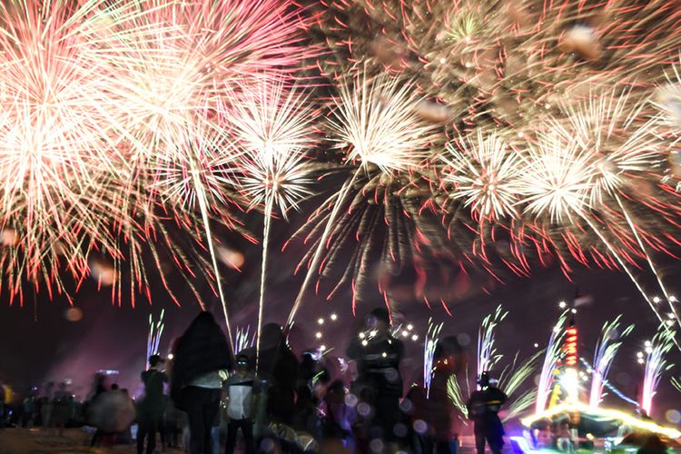 Sejumlah warga masyarakat menikmati pesta kembang api  di Pantai Lagoon, Taman Impian Jaya Ancol, Jakarta, Rabu (1/1/2020). Pesta kemang api tersebut untuk menyambut tahun baru 2020.