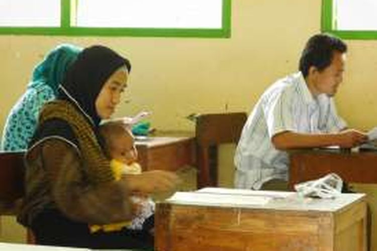 Anik (32) mengerjakan UN Paket C di SMPN 3 Ungaran, kabupaten Semarang, Kamis (7/4/2016) sambil mengasuh bayinya.