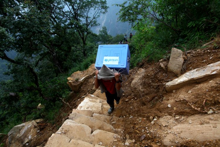 Petugas kesehatan membawa vaksin dalam perjalanan ke kampanye vaksinasi campak, rubella dan polio di Kabupaten Gorkha pada tahun 2015
