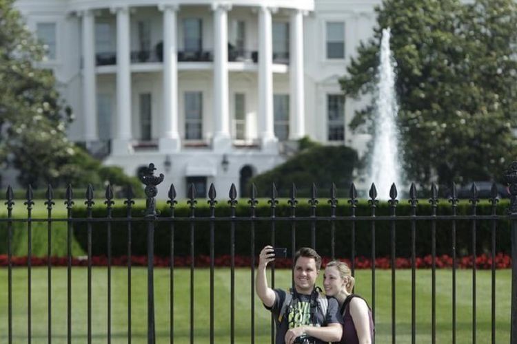 Sepasang turis melakukan swafoto di luar pagar bagian selatan Gedung Putih, Washington DC, AS pada 28 Mei 2015. 