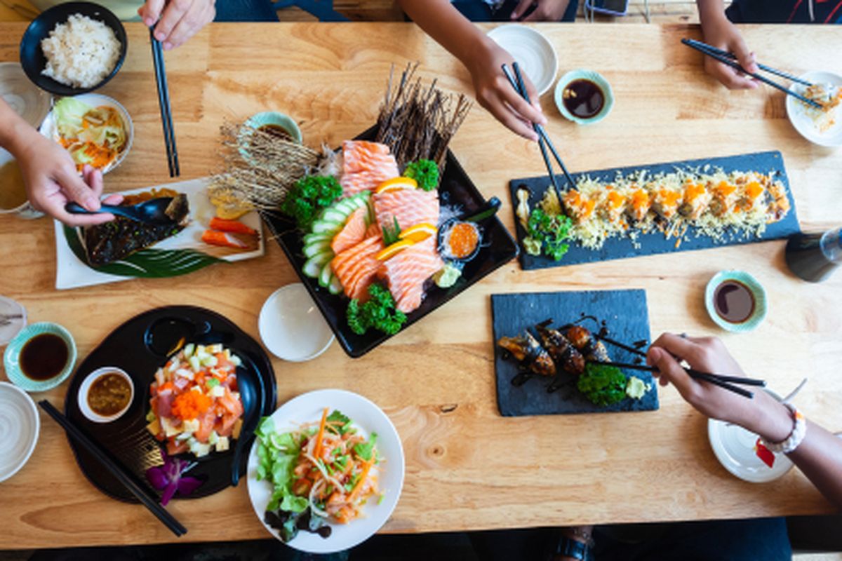 Satu set sushi di atas meja kayu di restoran Jepang, irisan salmon segar untuk menu sushi. Pesta teman atau keluarga makan sushi menggunakan batang bambu