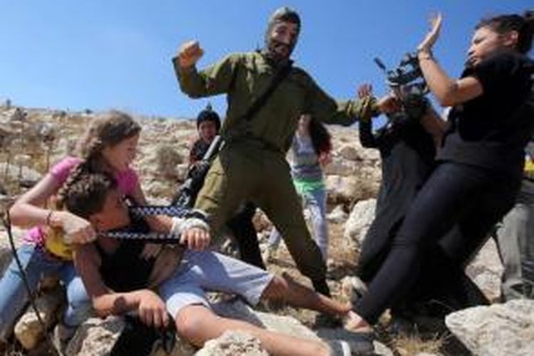 Wanita Palestina berjuang membebaskan seorang bocah yang ditangkap seorang tentara Israel (tengah) dalam bentrokan antara tentara Israel dengan demonstran Palestina di Desa Nabi Saleh, Tepi Barat, dekat Ramallah, Jumat (28/8/2015).