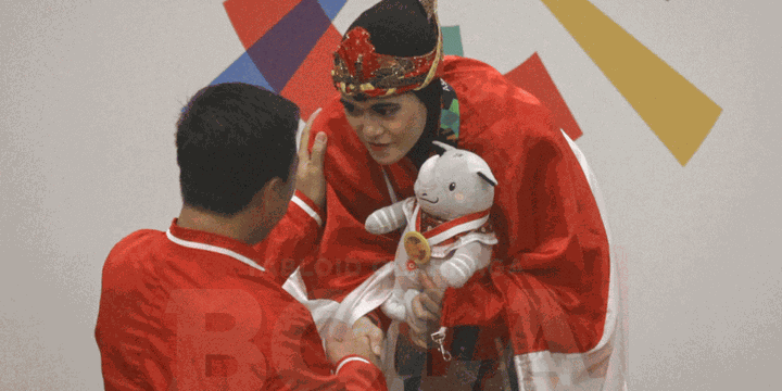 Atlet pencak silat Puspa Arumsari dikalungi medali oleh Menpora Imam Nahrawi seusai meraih medali emas Asian Games 2018, 27 Agustus 2018. 