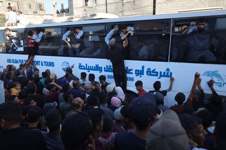 Warga Gaza memanjat bus untuk menyambut tahanan Palestina yang dibebaskan Israel sesuai ketentuan gencatan senjata, di luar rumah sakit Nasser, Khan Yunis, Jalur Gaza, Senin (13/10/2025).
