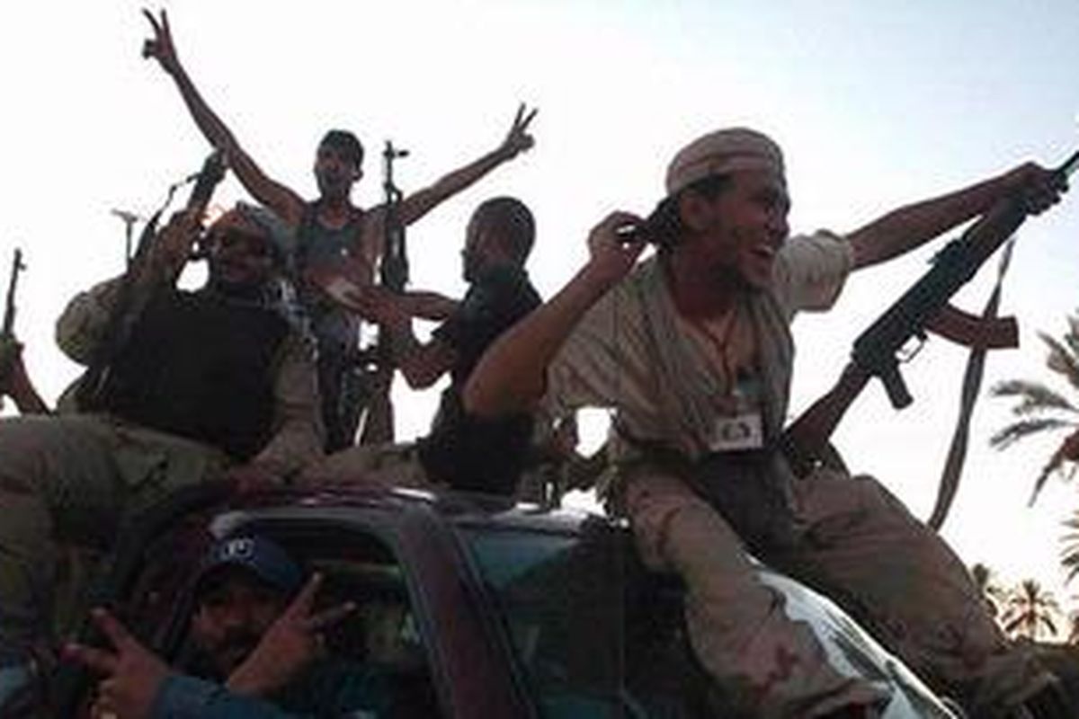 Sekelompok pemberontak Libya tersenyum dan membuat tanda-tanda perdamaian saat mereka terus maju ke dalam kota Tripoli, Minggu (21/8/2011). 