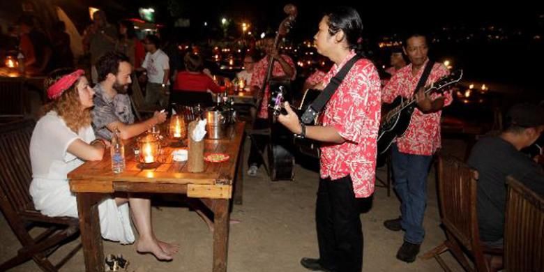 Grup musik menghibur turis asing saat makan malam di pinggir pantai Jimbaran, Bali, Jumat (21/6/2013). Kawasan Jimbaran merupakan salah satu tempat tujuan wisatawan selama berlibur di Bali, sejumlah tempat wisata seperti Jimbaran fish market dan Pura Uluwatu berada dekat dengan kawasan ini.  