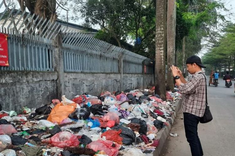 Seorang jurnalis saat mengambil gambar tumpukan sampah di sepanjang jalur kawasan industri di Kabupaten Tangerang, Banten. 