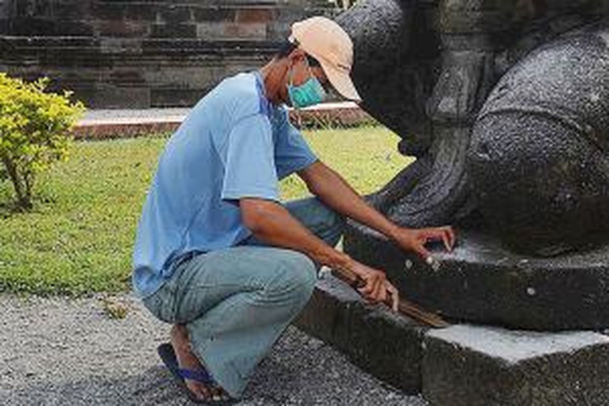 Edi Suyanto (40), juru pelihara kompleks Candi Penataran, di Desa Penataran, Kecamatan Nglegok, Blitar, Jawa Timur, membersihkan arca dari abu dan kerikil letusan Gunung Kelud yang terletak 10 kilometer dari candi tersebut, Sabtu (15/2/2014). Tak ada kerusakan pada candi akibat letusan tersebut. 