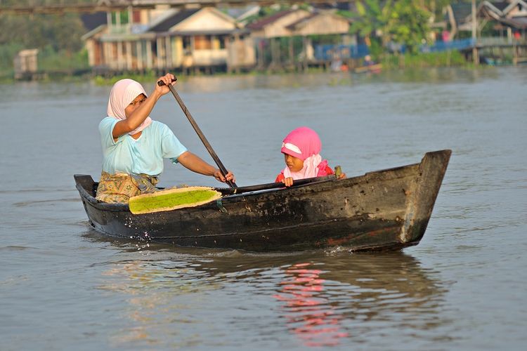 Wanita Suku Banjar dan anaknya di atas perahu DOK. Shutterstock/Robby Fakhriannur