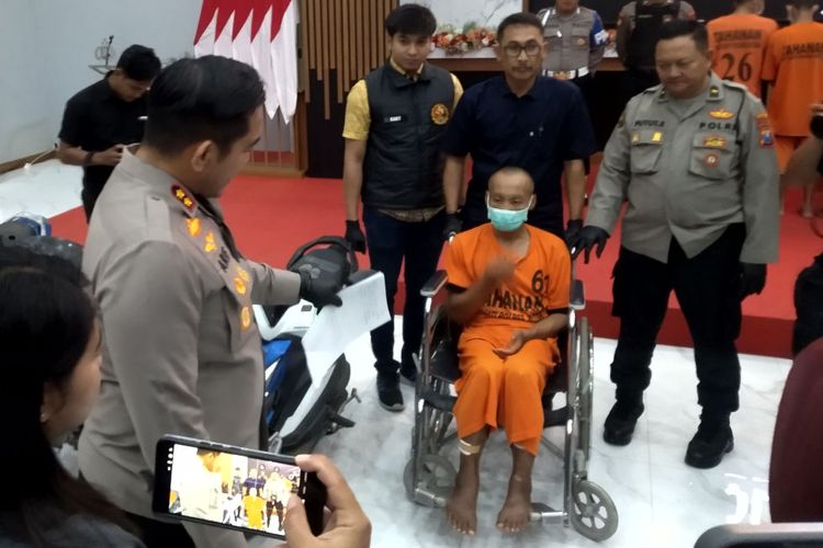 T (40), residivis kasus curanmor yang ditembak kedua kakinya, duduk di kursi roda saat dihadirkan pada konferensi pers di Mapolres Blitar, Jumat (7/11/2025)
