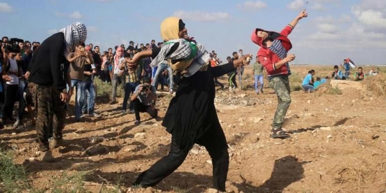 Perempuan Palestina bersama warga melempar batu ke arah tentara Israel dalam bentrokan yang terjadi di Jalur Gaza, 9 Oktober 2015.