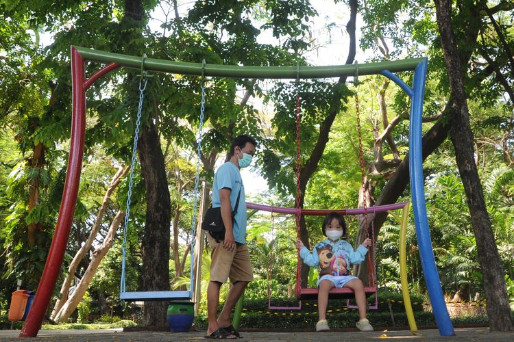 Seorang ayah mengajak anaknya bermain di Taman Flora, Surabaya, Jawa Timur.