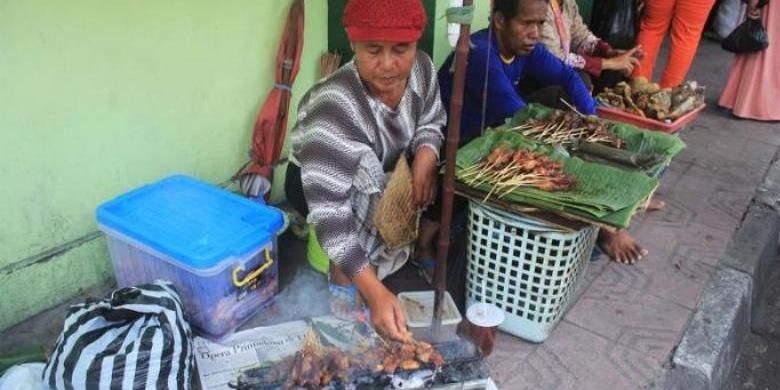 Ponijah membakar sate dagangannya.