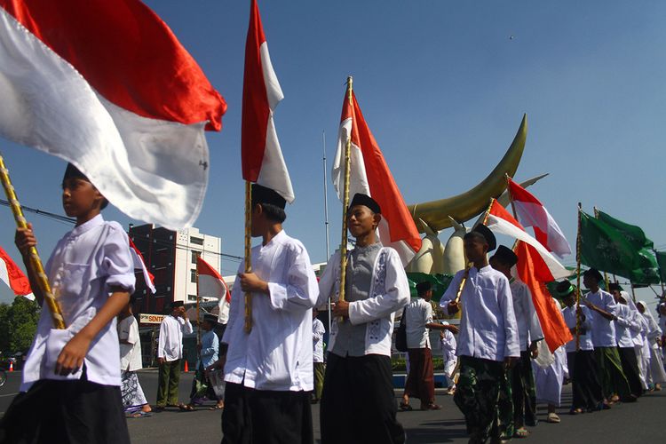 Peserta membawa bendera merah putih saat mengikuti Kirab Hari Santri Nasional di Perempatan Kartonyono, Ngawi, Jawa Timur, Senin (21/10/2019). Kirab Hari Santri Nasional tersebut diikuti ratusan peserta dari berbagai sekolah, pondok pesantren serta lembaga pendidikan berbasis ke-Islaman.