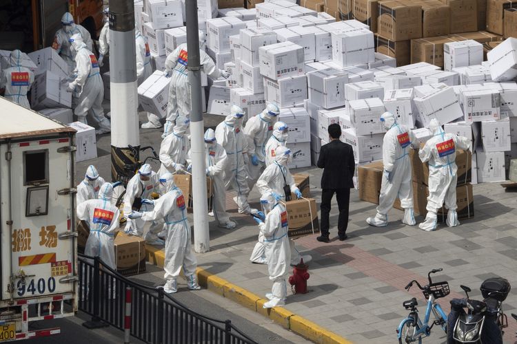 Workers unload supplies including boxes of masks in Shanghai on Sunday, April 10, 2022. China's largest city of Shanghai will soon begin lifting lockdown in communities that report no positive cases within 14 days after another round of Covid-19 testing, authorities said Saturday. (Chinatopix via AP)