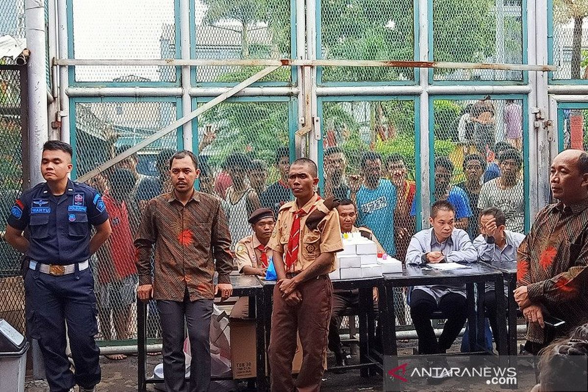 Sejumlah tahanan dan narapidana Lapas Klas I Cipinang, Jakarta Timur dijaga oleh sejumlah petugas gabungan saat mereka menyaksikan jalannya pemberian remisi khusus Natal 2019, Rabu (25/12/2019). 