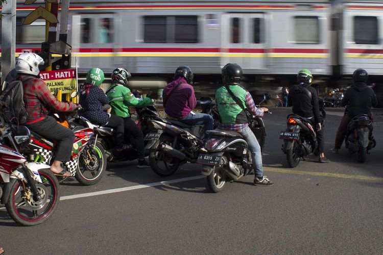 Pengendara menunggu kereta lewat di perlintasan kereta api wilayah Bumi Bintaro Permai, Pondok Aren, Jakarta Selatan, Sabtu (22/2/2020). Tidak berfungsinya palang pintu di perlintasan kereta api sejak 2 tahun lalu mengancam keselamatan warga.