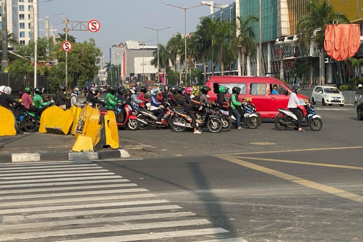 Para pengendara sepeda motor dan pengemudi angkot yang melewati marka jalan batas garis putih di lampu lalu lintas di Persimpangan Emporium, Jalan Pluit III Raya, Penjaringan, Jakarta Utara, Selasa (14/11/2023)