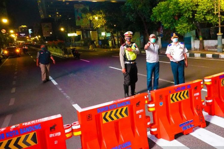 Petugas melakukan penutupan jalan di Kota Bandung pada malam hari.