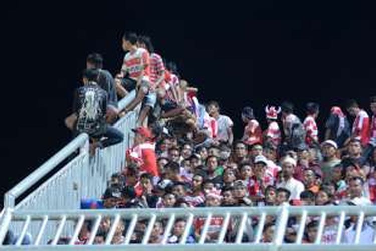 Suporter Madura United (MU) menempati pagar tribun dan tembok pagar untuk menikmati pertandingan MU melawan Persija. Dalam pertandingan ini banyak suporter yang tidak bisa masuk ke lapangan meskipun sudah punya tiket.