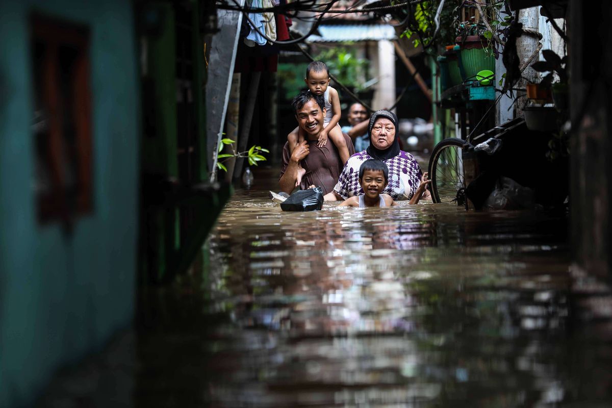 Satu keluarga melintasi lorong kecil saat banjir di Jalan Karet Pasar Baru, Karet Tengsin, Jakarta Pusat, Selasa (25/2/2020). Hujan deras sejak Senin dini hari membuat sejumlah daerah di Ibu Kota tergenang banjir.