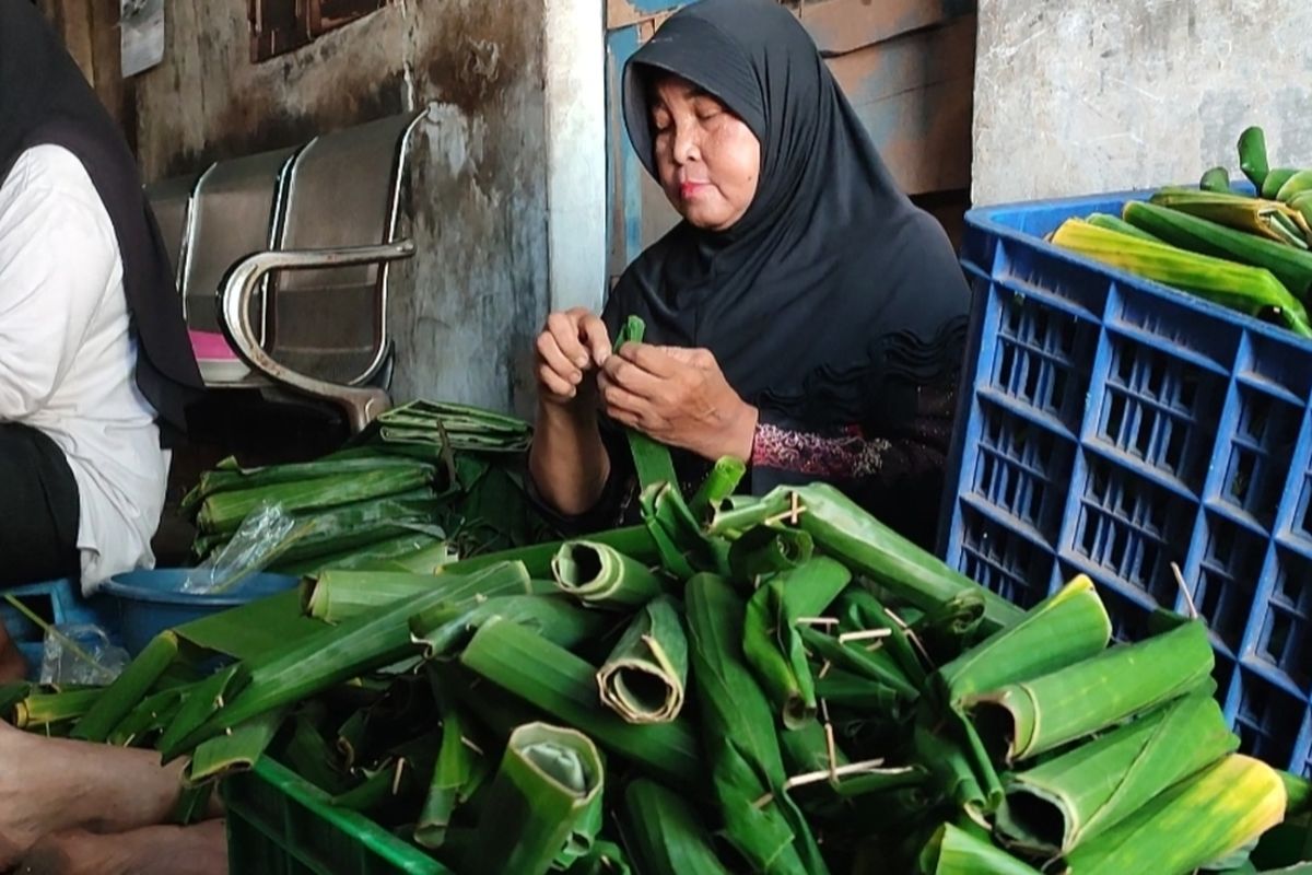 Nurlaela (42), Nurlaeli , dan Yani (62), pembuat lontong di Jalan Kandang Perahu, Kelurahan Karyamulya Kecamatan Kesambi Kota Cirebon Jawa Barat memasukan beras ke dalam daun pisang wadah lontong, di rumahnya, Kamis (22/2/2024) petang.
