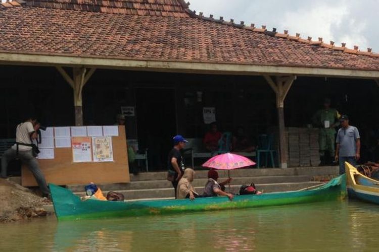 Warga Desa Mintobasuki, Kabupaten Pati, Jawa Tengah, menyalurkan hak pilihnya dalam Pilkada serentak 2017 ini meski dalam keadaan banjir, Rabu (15/2/2017). Untuk menuju ke tempat pemungutan suara, mereka menggunakan perahu sebagai sarana transportasi.