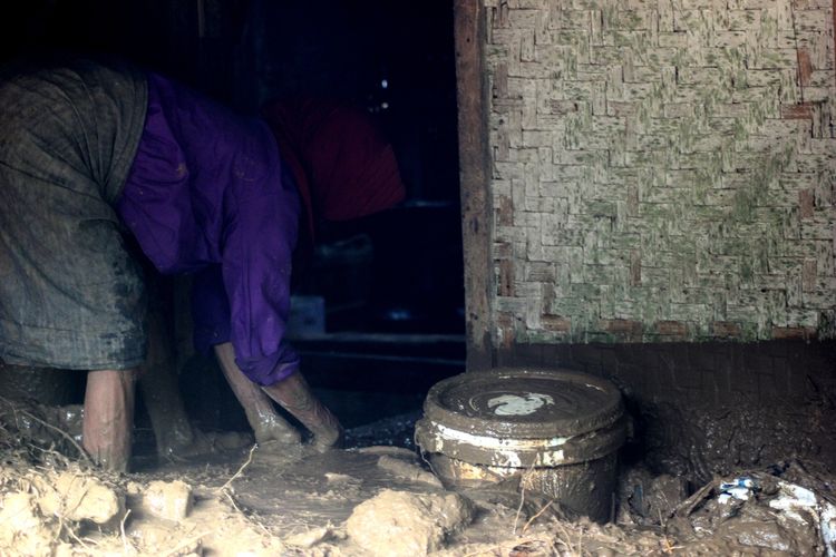 Seorang warga korban longsor di Desa Belendung, Desa Karangnunggal, Kecamatan Cibeber, Kabupaten Cianjur, Jawa Barat, tengah membersihkan lumpur yang dibawa material longsor dari dalam rumahnya, Minggu (22/3/2020).