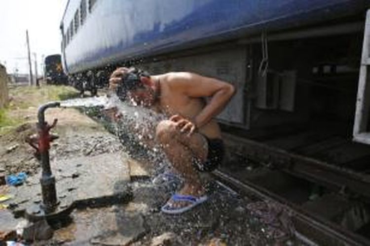 Seorang pria menyiram tubuhnya dengan air di stasiun kereta api Allahabad, India untuk mengurangi rasa panas akibat suhu udara yang sangat tinggi. Terpaan udara panas di India selama sepekan terakhir telah menewaskan setidaknya 1.500 orang.