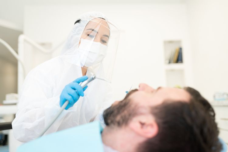 Ilustrasi dokter gigi melakukan prosedur perawatan gigi pada pasien menggunakan alat pelindung diri (APD) untuk mencegah penularan virus corona penyebab Covid-19.
