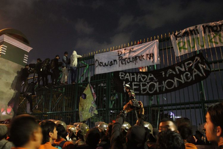 Mahasiswa menaiki pagar Gedung DPR/MPR pada aksi penolakan RKUHP , Jalan Gatot Subroto, Senayan, Jakarta Pusat, Senin (23/9/2019).