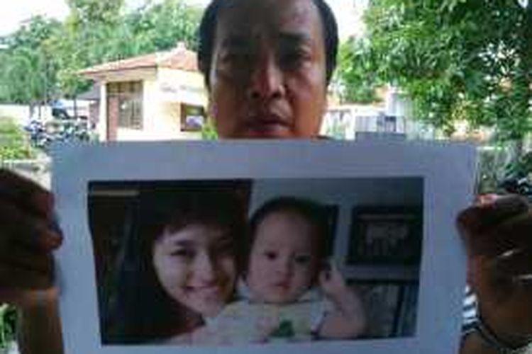 Muhamad Taufik menunjukkan foto putri dan cucunya yang hilang