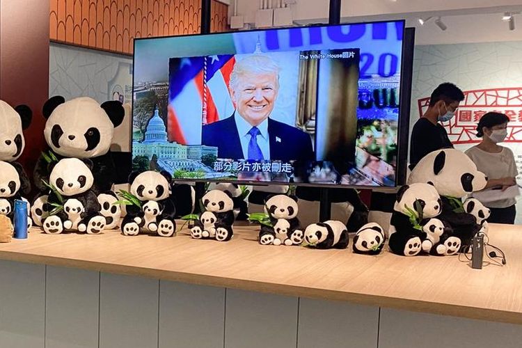 Sebuah televisi dikelilingi oleh belasan mainan boneka panda yang menarik perhatian anak-anak.