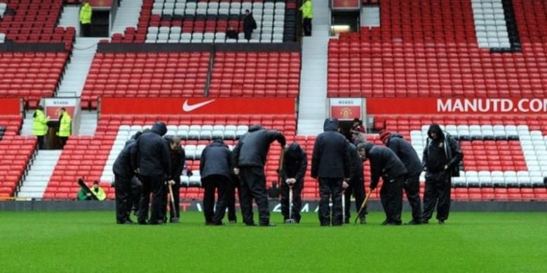 Para pekerja sedang mengurus lapangan Stadion Old Trafford.