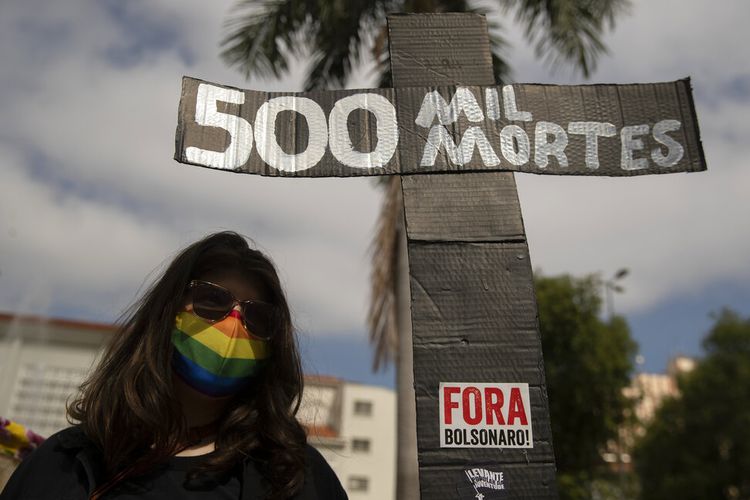 A woman, wearing a protective face mask, holds a sign in the shape of a cross with a message that reads in Portuguese;500 k deaths, during a protest against Brazilian President Jair Bolsonaro and his handling of the pandemic and economic policies protesters say harm the interests of the poor and working class, in Cuiaba, Brazil, Saturday, June 19, 2021. Brazil is approaching an official COVID-19 death toll of 500,000 ? second-highest in the world. (AP Photo/Andre Penner)