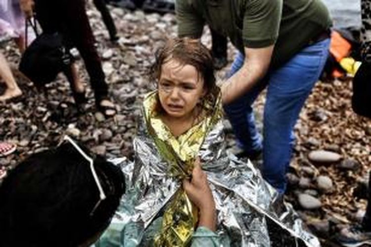 Seorang anak perempuan pengungsi Suriah menangis saat tiba di Pulau Lesbos, Yunani, setelah menyeberangi laut Aegean dari Turki, 28 September 2015. 