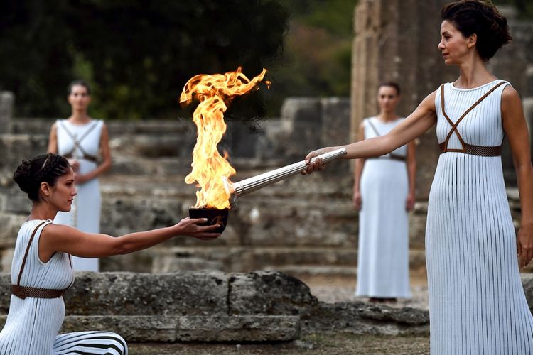 Aktris Yunani Katerina Lechou (kanan) memainkan peran sebagai Pendeta Agung dengan menyalakan obor dalam upacara tradisional Penyalaan Api untuk Olimpiade Musim Dingin Pyeongchang 2018, di Kuil Hera, Kota Olympia, Yunani, Selasa (24/10/2017). Obor Olimpiade ini akan tiba di Korea Selatan pada 1 November mendatang dan akan dibawa keliling dalam estafet yang akan berakhir 100 hari kemudian, bertepatan dengan upacara pembukaan di Pyeongchang, 9 Februari 2018.