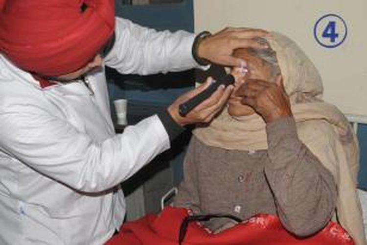 Seorang dokter di RS Amritsar, Jumat (5/12/2014), tengah memeriksa mata Shinder Kaur, yang kehilangan penglihatan setelah menjalani operasi katarak gratis di negara bagian Punjab bulan lalu. 