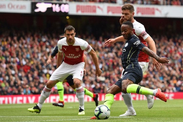 Pemain sayap Manchester City, Raheem Sterling, mencoba melepas tembakan saat dikawal dua pemain Arsenal pada pertandingan Premier League di Stadion Emirates, 12 Agustus 2018. 