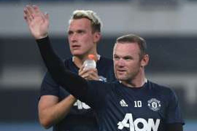 Penyerang Manchester United, Wayne Rooney, melambaikan tangan ke arah suporter saat menjalani sesi latihan di Beijing, China, pada Sabtu (24/7/2016).