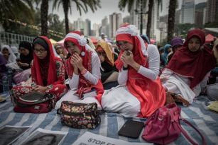 Para tenaga kerja Indonesia menggelar doa bersama di Victoria Park, Hongkong, Minggu (9/11/2014), untuk dua rekan mereka yang tewas dibunuh seorang warga negara Inggris, Rurik Jutting. 