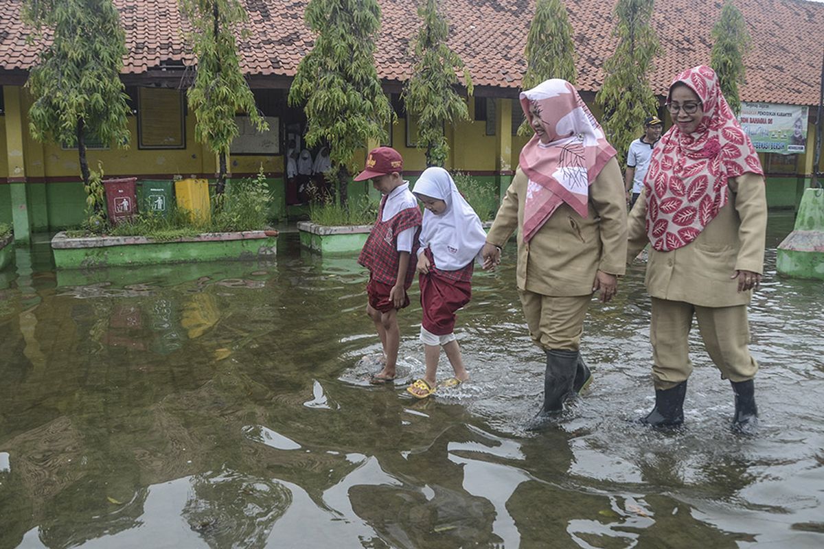 Sejumlah guru dan murid SDN 05 beraktivitas saat banjir di daerah Pondok Ungu, Kabupaten Bekasi, Jawa Barat, Senin (6/1/2020). Hari pertama sekolah terjadi banjir sejak pukul 05.00 pagi akibat luapan kali.