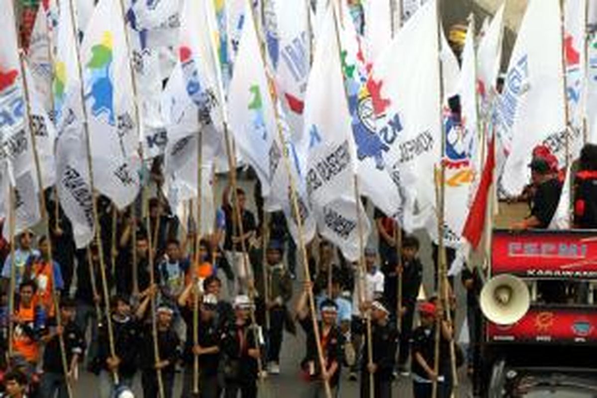 Ribuan buruh dari berbagai organisasi berunjuk rasa memperingati Hari Buruh Internasional, melintasi Jalan MH Thamrin, Jakarta Pusat, Kamis (1/5/2014). Hari Buruh Internasional ditetapkan sebagai hari libur nasional untuk kali pertama di tahun ini, diperingati dengan berunjuk rasa menuntut upah layak, penghapusan outsourcing, dan penolakan terhadap undang-undang Badan Penyelenggara Jaminan Nasional. TRIBUNNEWS/HERUDIN