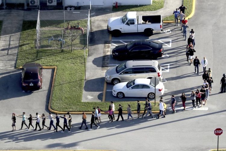 Murid sekolah dievakuasi dari SMA Marjory Stoneman Douglas High School di Parkland, Florida, pada Rabu (14/2/2018), setelah seorang penembak melepaskan tembakan ke sekolah dan menewaskan 17 orang. (South Florida Sun-Sentinel via AP)